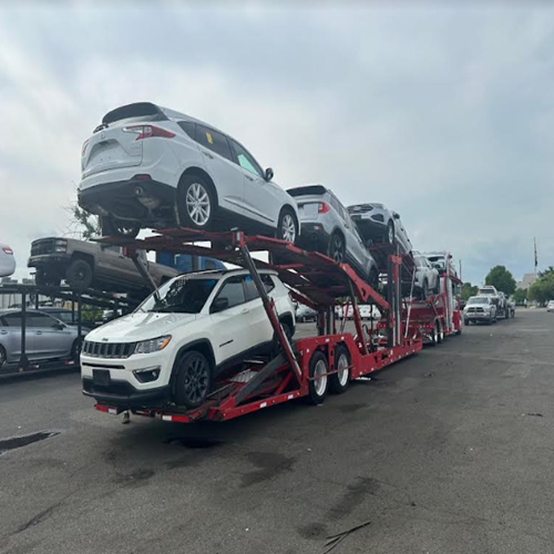 Car hauler trailer fully loaded with multiple vehicles, parked on a residential street corner during delivery