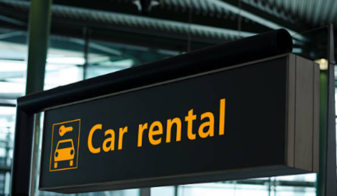 Billboard advertising car rental company services on a city street