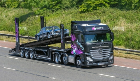 classic car shipping truck driving on the road