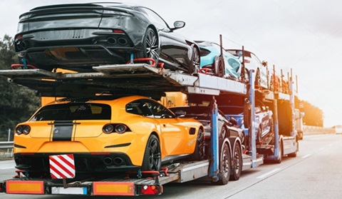Open exotic car shipping trailer carrying multiple exotic cars for cross country transport